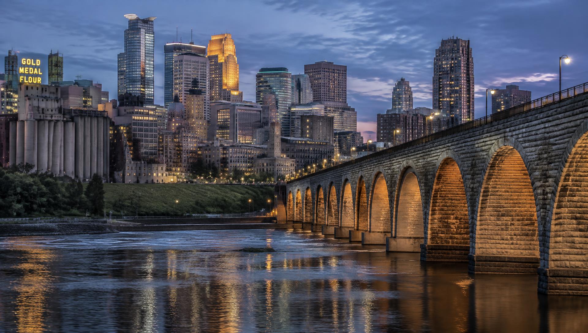 Minneapolis riverfront at dusk with theater and mill district buildings